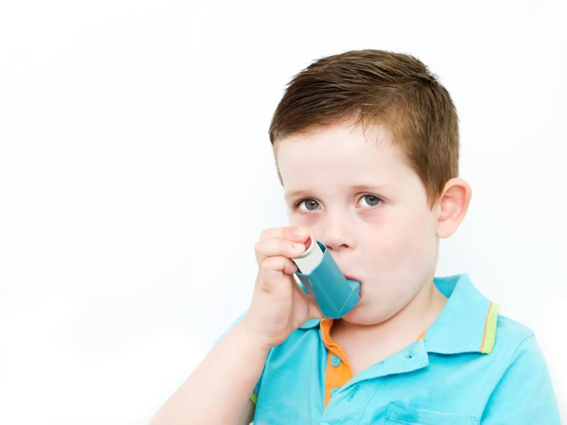 little boy using his asthma pump little boy using his asthma pump white background