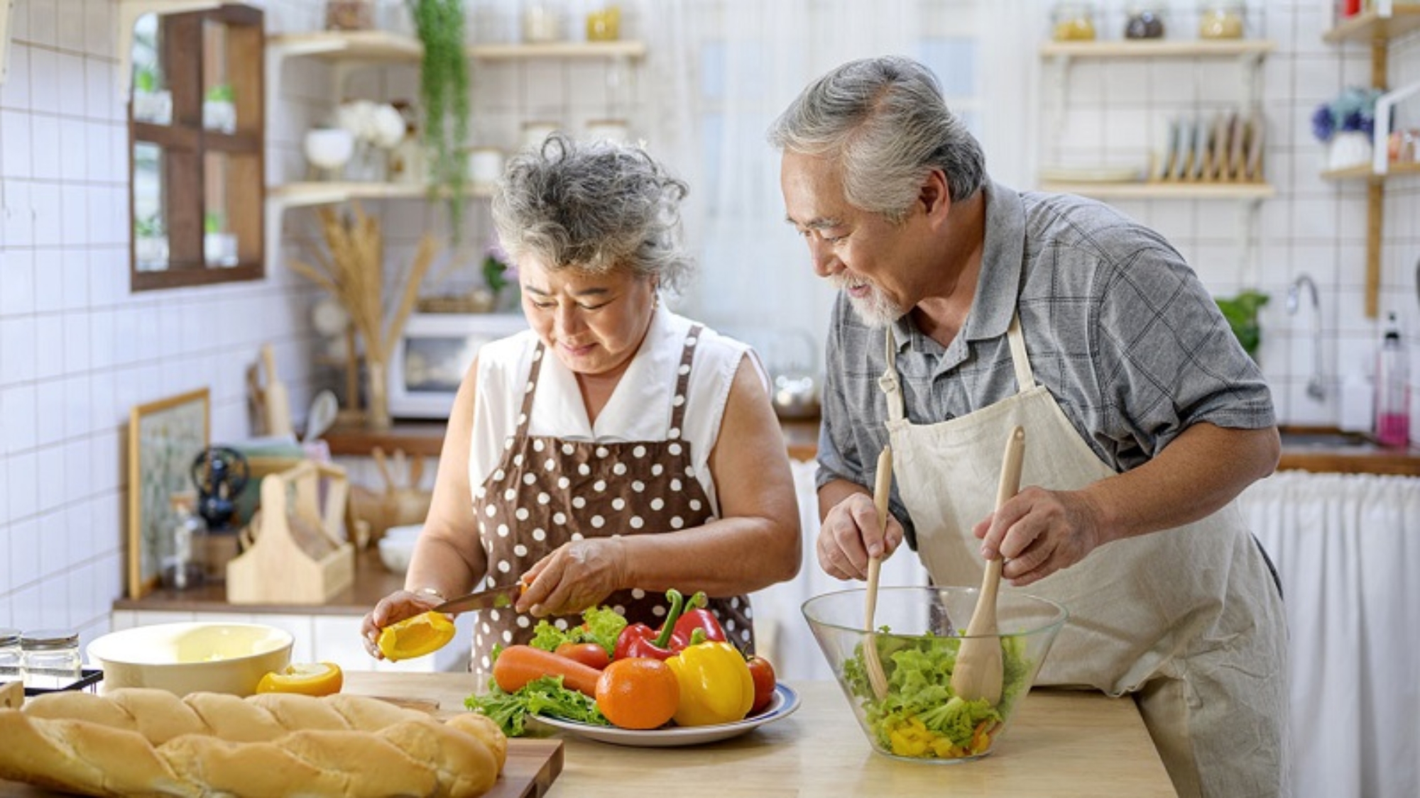Asian elderly happy couple making healthy food in the kitchen at home. Elderly spending time together concept.