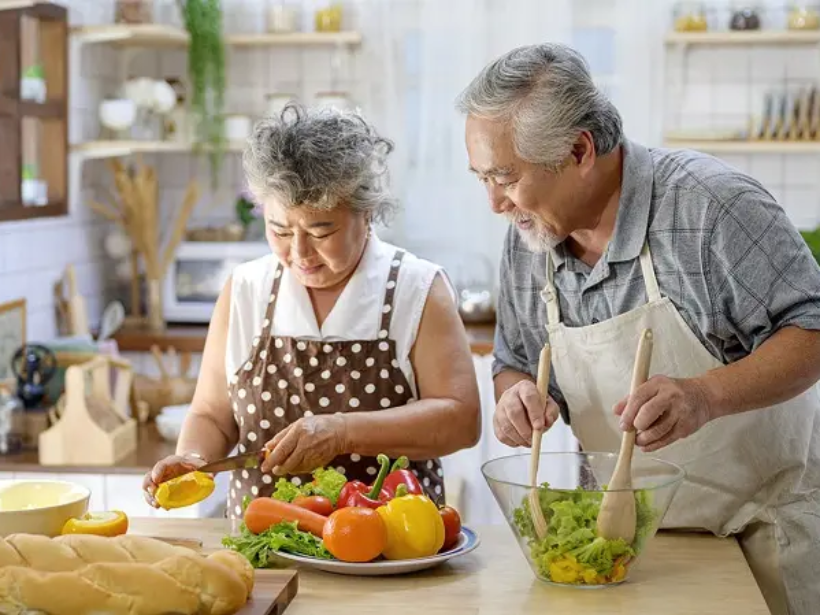 Asian elderly happy couple making healthy food in the kitchen at home. Elderly spending time together concept.